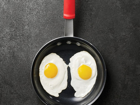 Ceramic nonstick fry pan releasing a fried egg, showing the easy-release benefits of ceramic cookware.