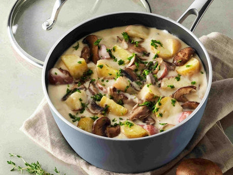 Creamy potato and mushroom stew made with a heavy cream substitute simmering in a Tramontina ceramic nonstick saucepan, finished with fresh parsley